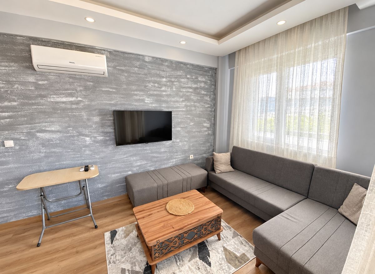Living room with a grey corner sofa, coffee table and wall-mounted TV